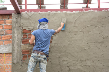 Obraz na płótnie Canvas Builder worker plastering concrete at wall