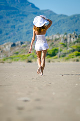 beautiful young woman takes a relaxing walk along a sandy beach 
