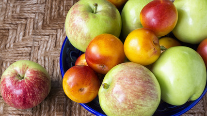 Fresh fruits: apples and plums on the plate