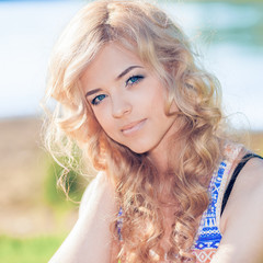 Naklejka premium Beautiful sunny portrait of a romantic and mysterious blonde girl
