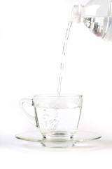 Pouring water into glass from a bottle, on white background
