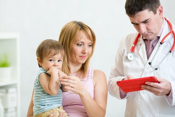 Pediatrician doctor examining child. Mother holding baby.
