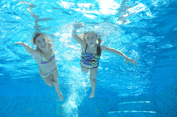 Children swim in pool underwater, happy active girls have fun in water