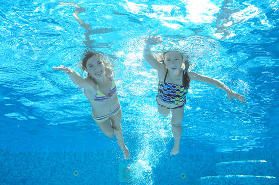 Children swim in pool underwater, happy active girls have fun in water, kids sport 