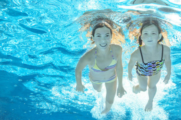 Obraz na płótnie Canvas Children swim in pool underwater, happy active girls have fun in water