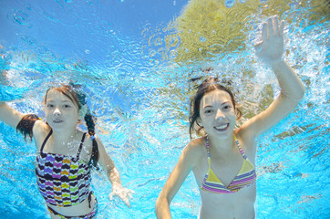 Obraz na płótnie Canvas Children swim in pool underwater, happy active girls have fun in water 