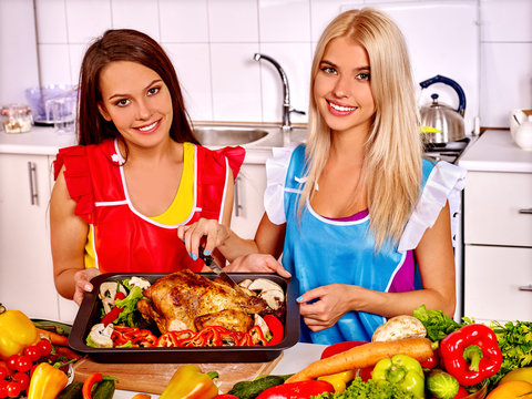 Women cooking chicken at kitchen.