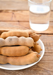 close up ripen sweet tamarinds in white disk put on wooden table