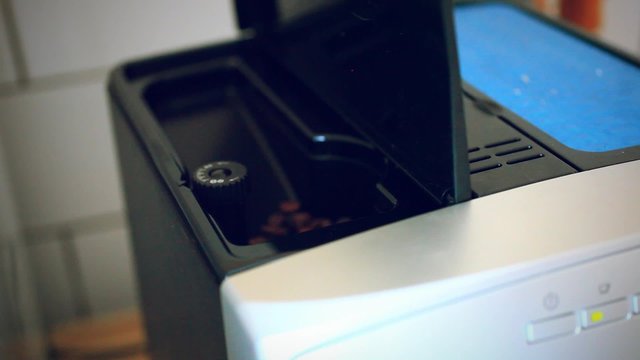 putting some coffee beans in the coffee machine
