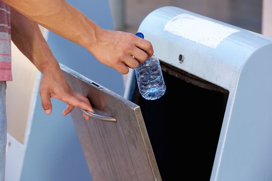 Man hand throwing away plastic bottle in recycling bin