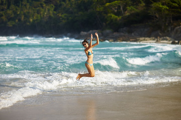 Happy young girl jumping on sea