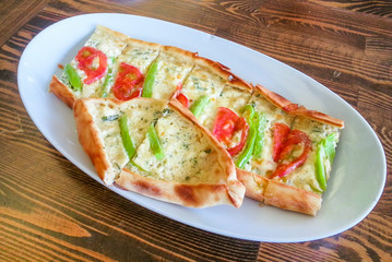 Sliced vegetarian Turkish pizza with green pepper, tomato and cheese