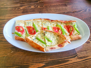 Sliced vegetarian Turkish pizza with green pepper, tomato and cheese