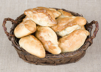 Homemade patties made by grandma in a wooden vintage basket on a gray sackcloth background