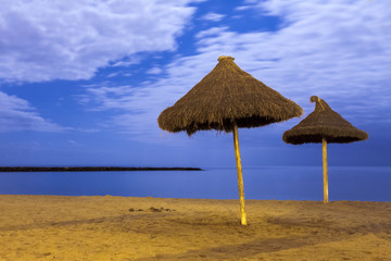  pair of sun parasols on empty beach at night