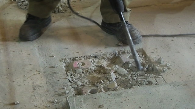 Industrial workers drill concrete with Electric plugger hammer  at construction site.
