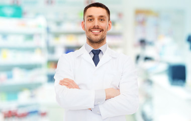 smiling male pharmacist in white coat at drugstore