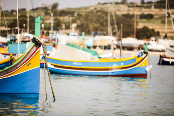 Fototapeta na wymiar Maltese Luzzu fishing boat, Marsaxlokk, Malta. Maltese fishing boats decorated in their familiar bright colors with eyes painted on the bows.