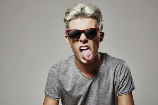 Junge mit weißen Haaren streckt Zunge raus