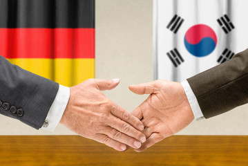 Vertreter Deutschlands und Südkoreas reichen sich die Hand