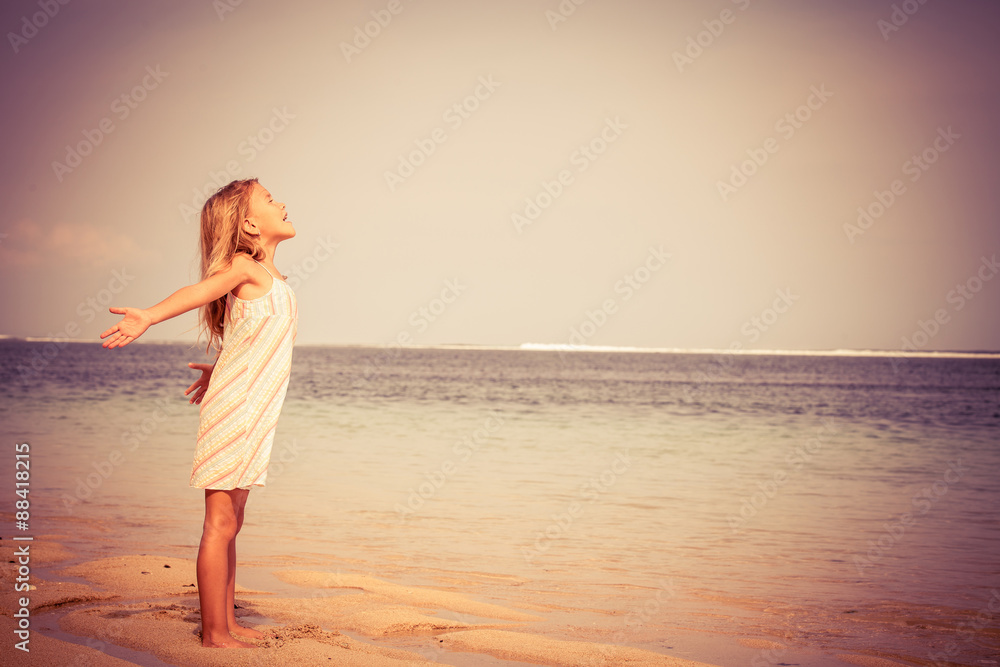 Wall mural Happy Little girl  standing on the beach