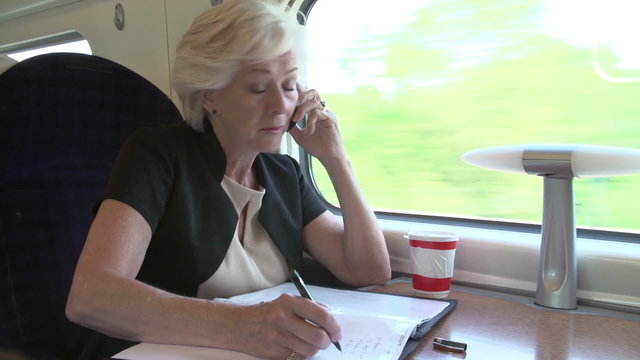 Businesswoman Commuting To Work On Train Using Mobile Phone
