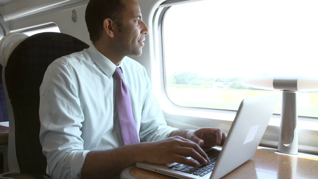 Businessman Commuting To Work On Train And Using Laptop
