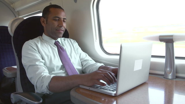 Businessman Commuting To Work On Train And Using Laptop
