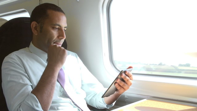 Businessman Commuting On Train Reading E Book
