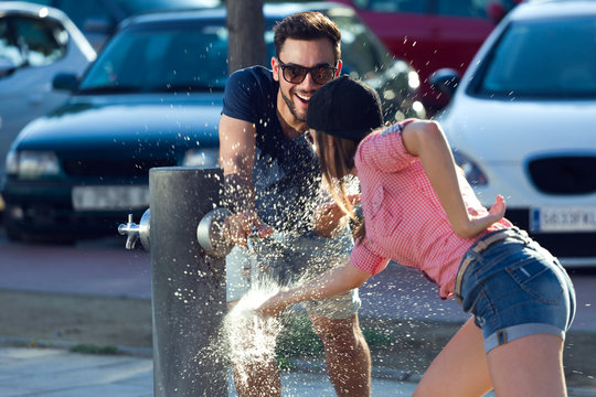 Portrait of two friends playing with a fountain in the street.
