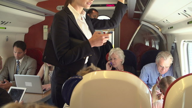 Businesswoman Using Mobile Phone On Busy Commuter Train
