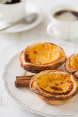 portuguese cookies with cinnamon on white dish with cup of coffee