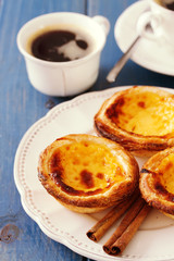 portuguese cookies with cinnamon on white dish with cup of coffee on blue wooden background