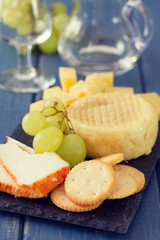 cheese with grapes and cookies and glass of white wine