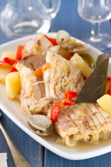 fish stew on white dish with wine on blue background