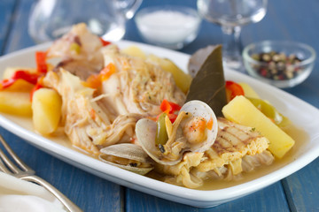 seafood stew on white dish with wine on blue background