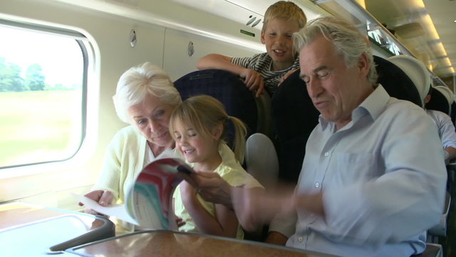 Grandparents And Grandchildren Relaxing On Train Journey
