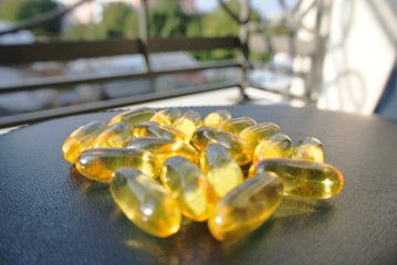 Heap of yellow omega 3 fish oil gel capsules on the black table. Food supplements; essential fatty...