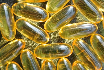 Closeup of omega 3 fish oil gel capsules on the black table, shot from above. Food supplements; essential fatty acids; healthy diet.