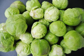 Closeup of a pile of fresh green Brussels sprouts on the black background. Healthy/clean eating concept; fresh, organic, unprocessed food; paleo diet.