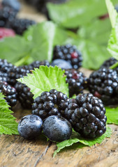 Fresh blackberries and blueberries with leaves on the old wooden