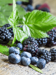 Fresh blackberries and blueberries with leaves on the old wooden