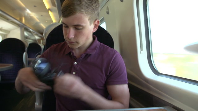 Young Man Listening To Music On Train Journey
