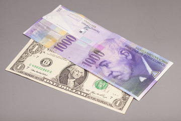 American dollars and Swiss franc currency isolated on gray