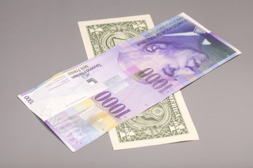 American dollars and Swiss franc currency isolated on gray