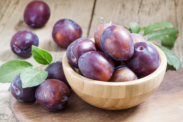 Delicious blue plums in a wooden bowl, selective focus