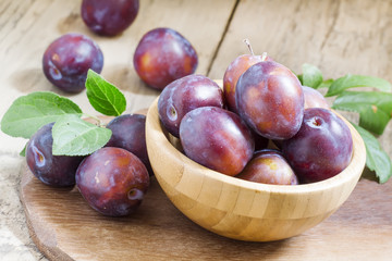 Delicious blue plums in a wooden bowl, selective focus