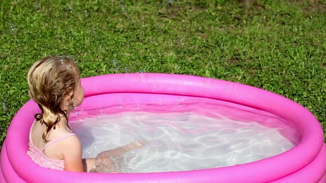 A girl playing in a water-filled kiddie pool