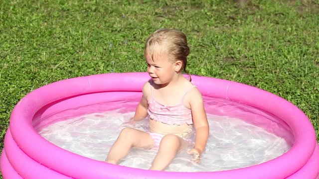 A delighted girl playing in a water-filled kiddie pool