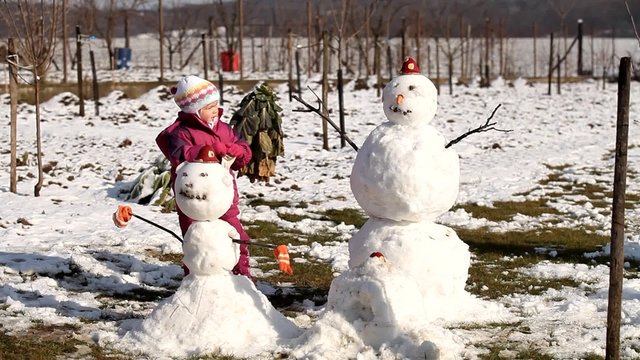 Happy little girl making two snowman